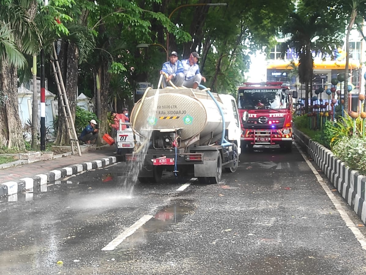 Truk tengki air milik Dinas Lingkungan Hidup (DLHK) Sidoarjo, sedang memberihkan jalan raya bekas tumpukan sampah