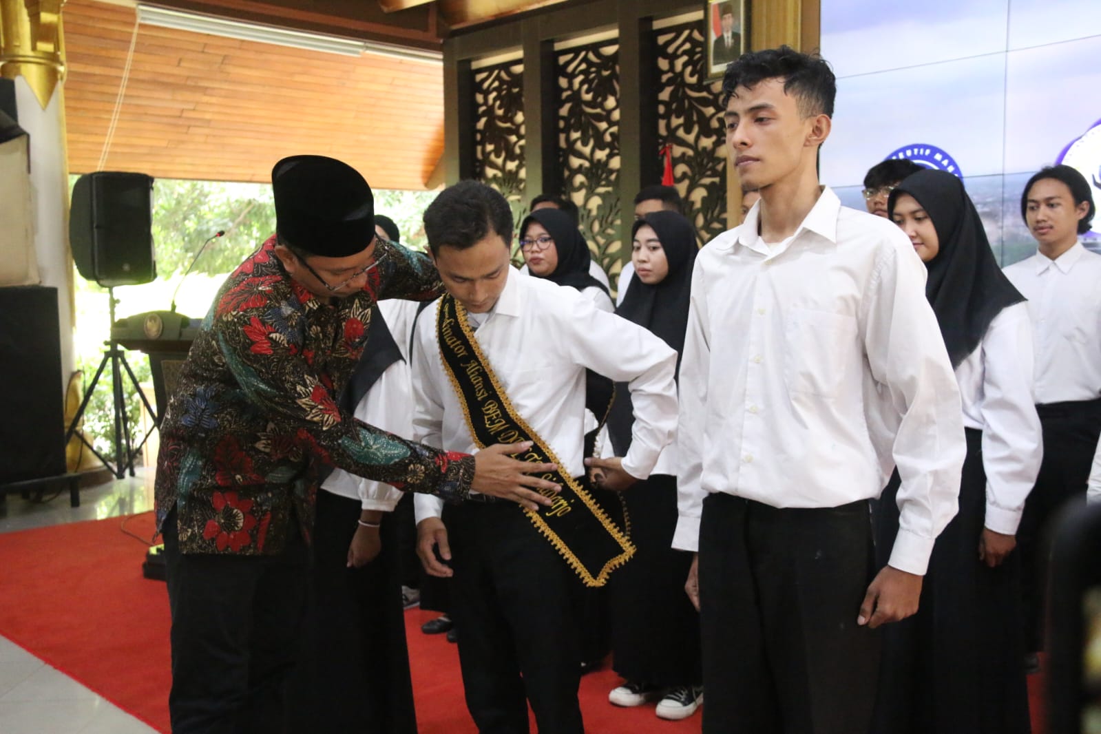 Bupati Sidoarjo, Ahmad Muhdlor Ali, saat menyematkan slempang pada Koordinator Aliansi BEM Delta M. Aditya Fathurrahman.