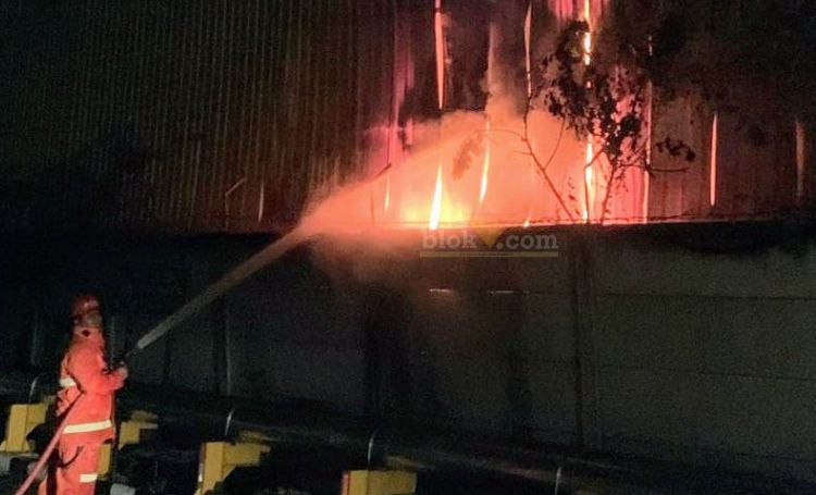 Petugas damkarla Gresik berusaha memadamkan api yang melahap Gudang PT Multi Trading Pratama. (blok-a.com/ivan)