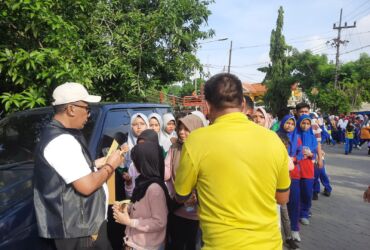 Teks Foto : Kadis Parporaekraf Gresik turun tangan membagikan kupon hadiah Jalan Sehat (blok-a.com/ivan)