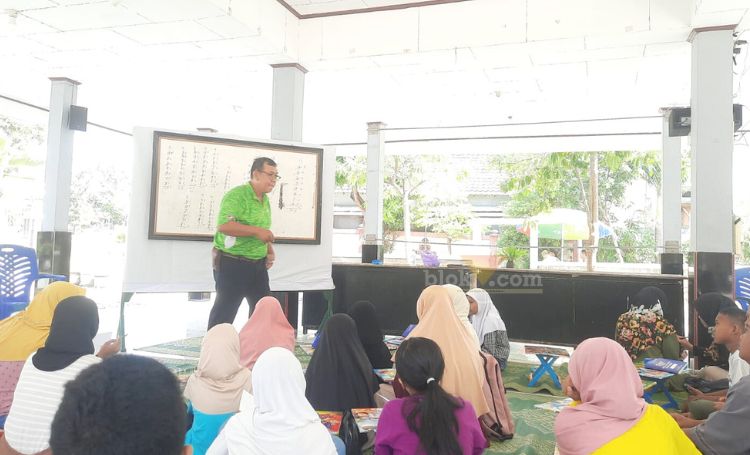 Edi Susanto bersama puluhan anak-anak saat les matematika gratis digelar di balai desa Yosowilangon. (blok-a.com/ivan)