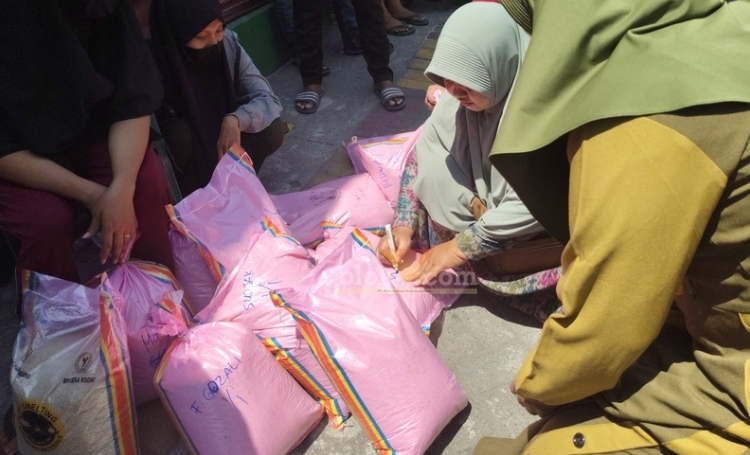 Ratusan emak-emak membawa beras CSR tak Layak Konsumsi ke Balai Desa Roomo, Manyar, Gresik. (blok-a.com/ivan)